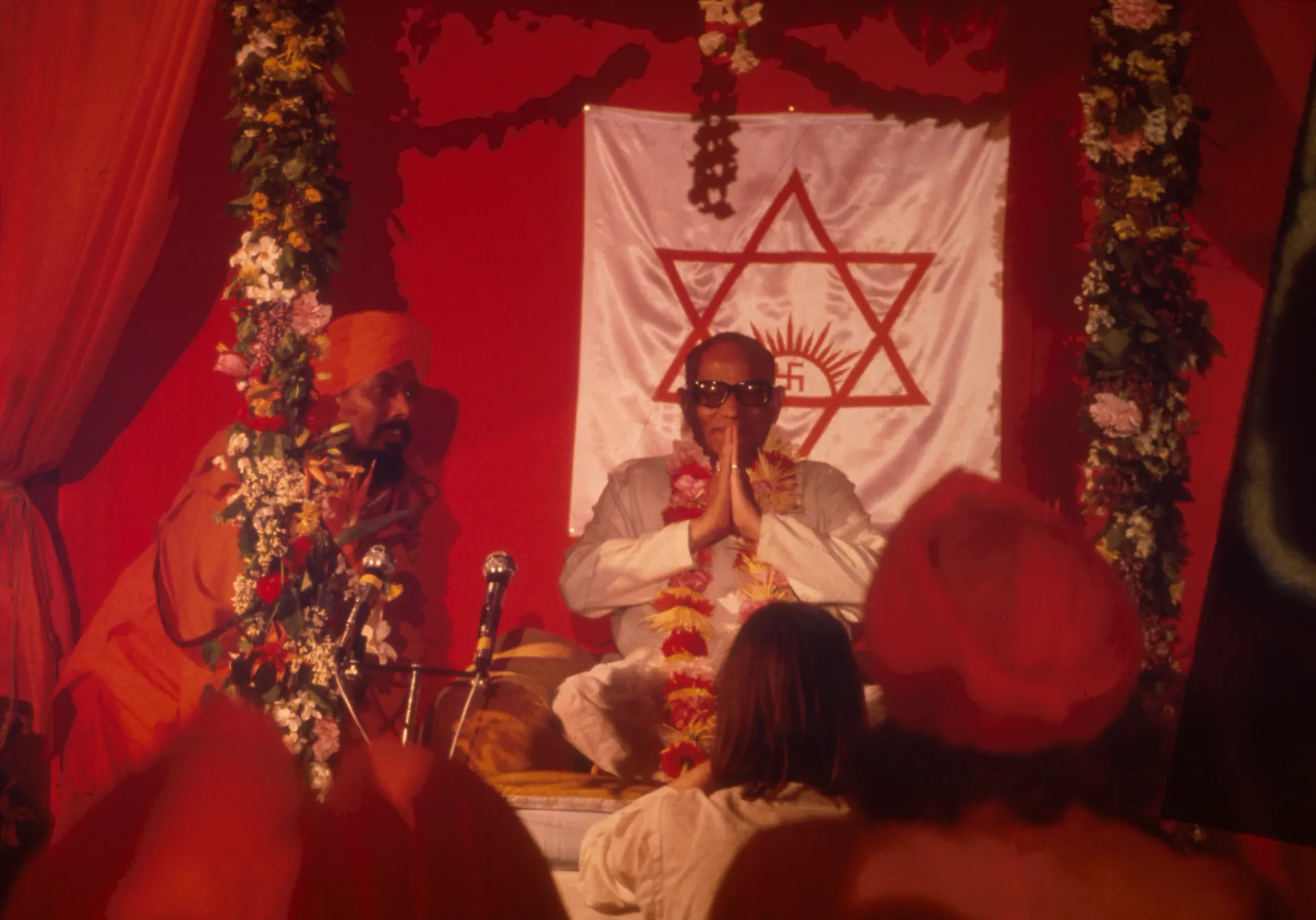 Shrii Shrii Anandamurti with folded hands at a decorated pandal