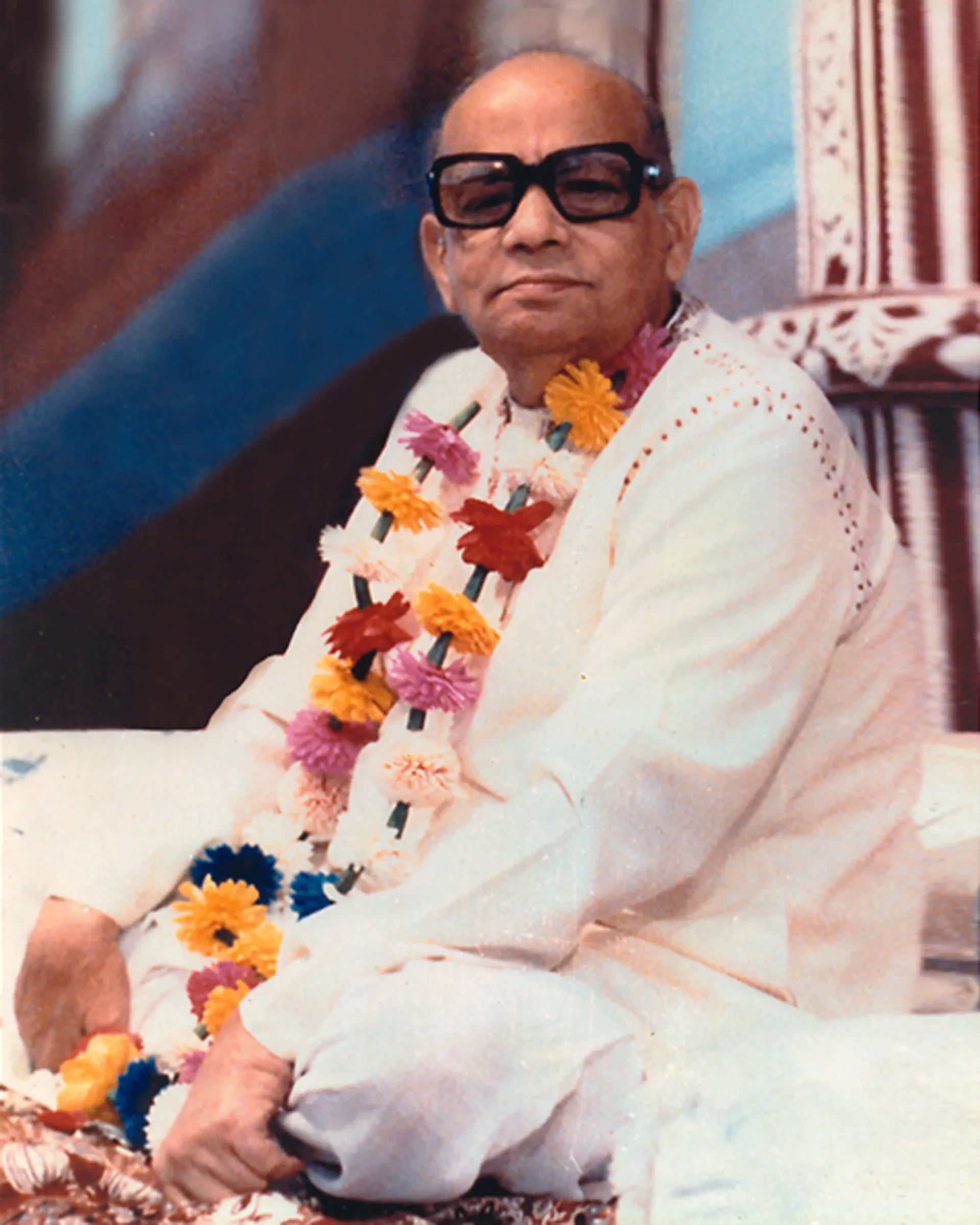 Shrii Shrii Anandamurti garlanded with flowers, seated